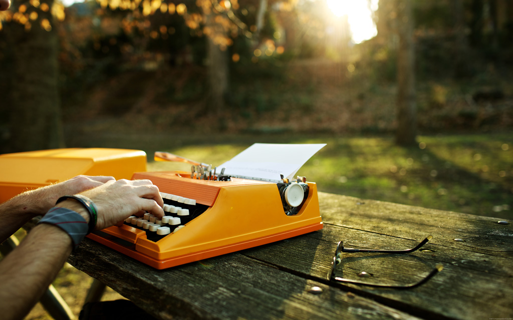 Hands on the orange typewriter in a park